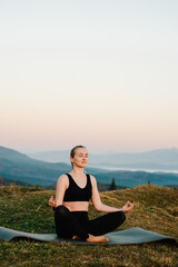 Naklejka na ściany i meble Woman practicing meditate and zen energy yoga in mountains. Healthy lifestyle concept. Young girl doing fitness exercise sport outdoors in beautiful landscape. Morning sunrise. Relax in nature.
