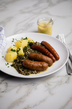 Oldenburger Gr&uuml;nkohl mit Pinkel, Kohlwurst, Senf und Kartoffeln auf Marmor Tisch