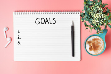 Inscription goal 2021 cup of coffee and green plant on a pink background