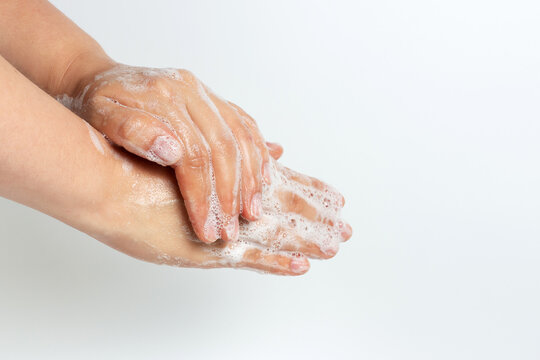 The girl washes her hands with soap and foam on white background