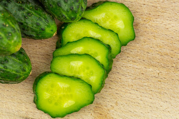 Slices of fresh, juicy cucumber on wooden cutting board