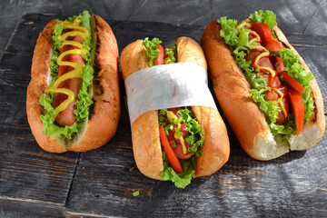 Hot dogs with various fillings. Dark background. food background with copy space. Hot dogs with mustard and ketchup, lettuce, cheese and tomatoes. Close up