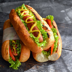 Hot dogs with various fillings. Dark background. food background with copy space. Hot dogs with mustard and ketchup, lettuce, cheese and tomatoes. Close up