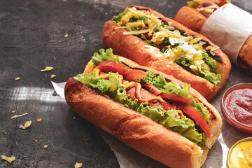 Hot dogs with various fillings. Dark background. food background with copy space. Hot dogs with mustard and ketchup, lettuce, cheese and tomatoes. Close up