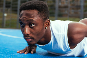 Young athletic dark-skinned African-American guy pushing off the floor, training. The concept of a healthy lifestyle