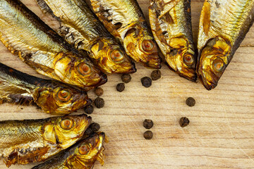 Golden, smoked sprats arranged on wooden cutting board