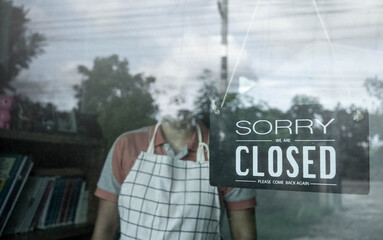 The woman store owner hanging closed sign in front door of her shop. Effect of corona virus or covid-19 outbreak 2020.