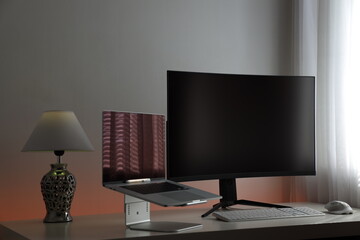 Computerarbeitsplatz mit einem flachen Laptop und einem gekrümmten und großen 4k Monitor mit...