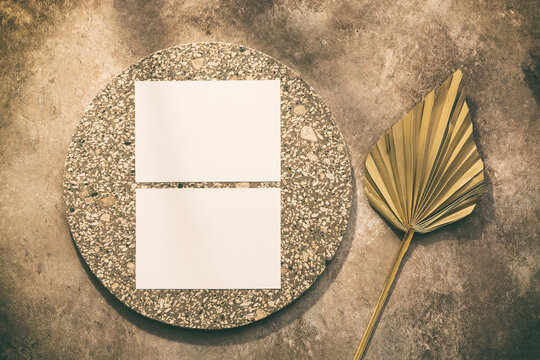 Blank Paper Business Cards Mockup On Granite Plate And Dry Palm Leaf Fan In The Sunlight. Brown Grunge Background. Modern Template For Branding Identity. Top View, Flat Lay.