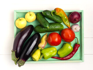 Tray with various vegetables on a white wooden background