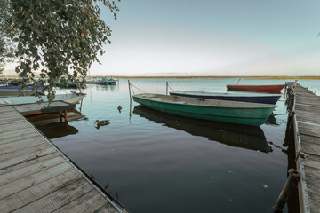 Pier with boats on the lake in early autumn evening. 