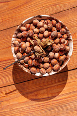 Hazelnuts in porcelain bowl on rustic wooden background. Raw fresh homegrowing nuts from house garden top view natural shadow. Organic dietary fiber, protein, vitamins source, healthy weight loss diet