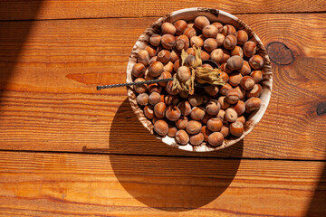 Hazelnuts in porcelain bowl on rustic wooden background. Raw fresh homegrowing nuts from house garden top view natural shadow. Organic dietary fiber, protein, vitamins source, healthy weight loss diet
