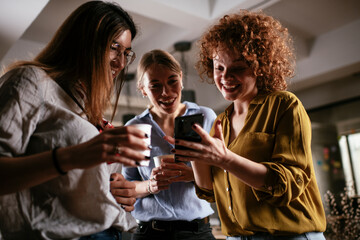 Girlfriends talking and laughing in office. Beautiful women drinking coffee in the office...