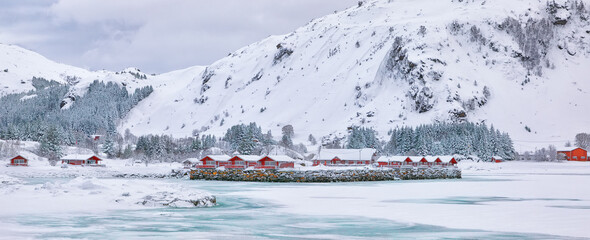 Winter scene with traditional Norwegian red wooden houses on the shore of Rolvsfjord in Valberg on Vestvagoy island at Lofotens