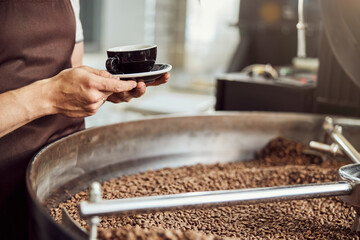 Male worker holding cup of coffee and saucer