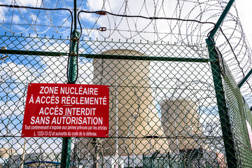 Security fence of a nuclear power plant in France with barbed wire and warning signs reading...