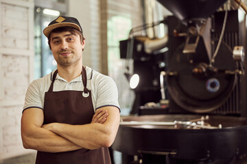 Handsome young man standing near coffee roasting machine