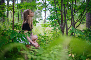 Practice of meditation and interaction with nature. Girl in green forest