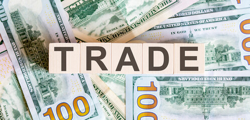 Concept words TRADE on wooden blocks on a beautiful background from dollar bills.
