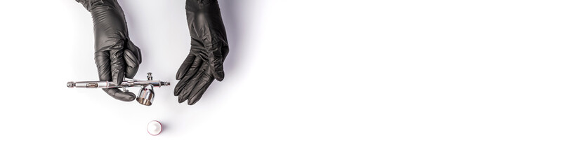 Manicure master painting in beige color fingernail using airbrush. Woman getting nail manicure....