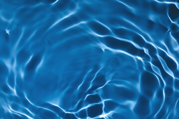 Fototapeta na wymiar Blurred transparent dark blue colored clear calm water surface texture with splashes and bubbles. Trendy abstract nature background. Water waves in sunlight with copy space.