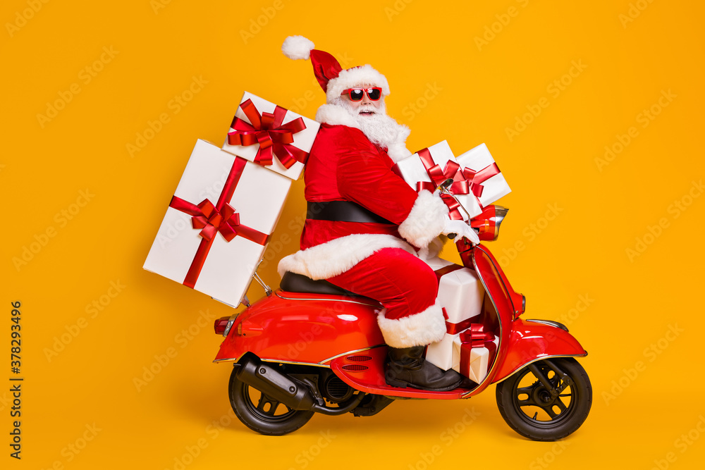 Wall mural Full size profile side photo of white grey hair bearded santa claus ride motorbike deliver x-mas christmas gifts on noel night wear headwear isolated bright shine color background