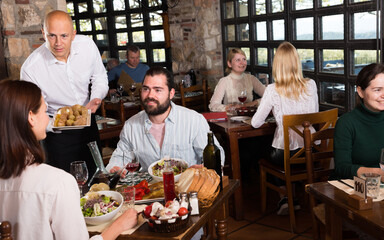Fototapeta na wymiar Waiter bringing order to visitors in rural restaurant. High quality photo