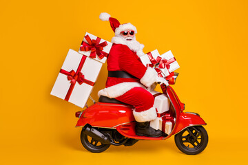 Full size profile side photo of white grey hair bearded santa claus ride motorbike deliver x-mas christmas gifts on noel night wear headwear isolated bright shine color background