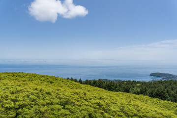 Fototapeta na wymiar 青い空と海と緑の山の風景　山頂からの景色