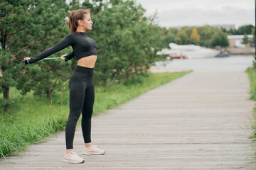 portrait of a confident strong woman leads a healthy lifestyle, preparing for exercises with a rope . Black comfortable tight clothing for sports. look away