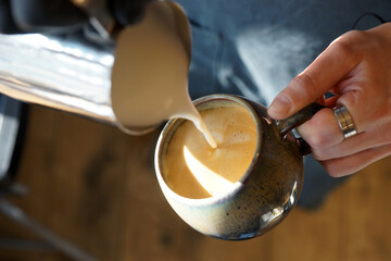 Barista prepares coffee in a paper cup