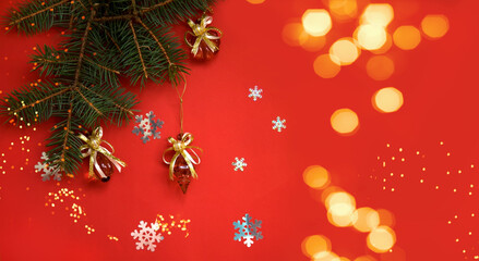 Spruce branch decorated with Christmas decorations on a red background with snowflakes and bokeh. christmas banner