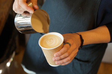 Fototapeta na wymiar Barista prepares coffee in a paper cup
