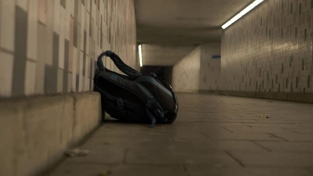 Rucksack left in lonely urban subway at night zoom in wide shot