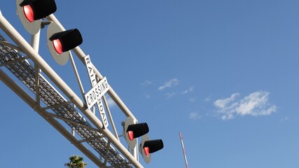 Level crossing warning signal in USA. Crossbuck notice and red traffic light on rail road intersection in California. Railway transportation safety symbol. Caution sign about hazard and train track