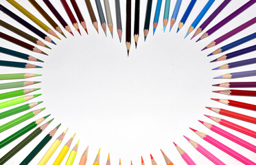 Colored pencils background with a variety of colors arranged in a heart shape, Selective Focus.