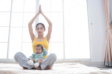 Asian mother fit and play Yoga for lose weight after delivery a new born baby in home, sports mother is engaged in fitness mom, mother, exercise and healthy concept.