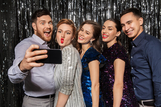 celebration, technology and holiday concept - happy friends taking selfie by smartphone at party