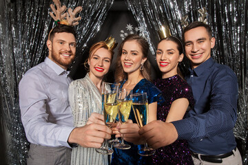 christmas, celebration and holidays concept - happy friends clinking champagne glasses at party