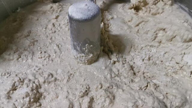 Close up for bread making process by using flour mixing machine in the factory. Stock footage. Preparation of dough with professional kneader machine at the manufacturing.