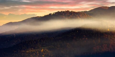 mountain landscape in autumn. fog glowing in morning light. dramatic sky with clouds at sunrise