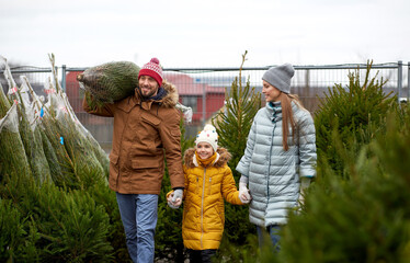family, winter holidays and people concept - happy mother, father and little daughter buying...