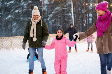 christmas, family and leisure concept - happy mother, father and daughter at outdoor skating rink in winter