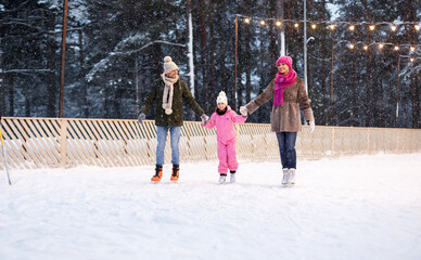 Fototapeta na wymiar christmas, family and leisure concept - happy mother, father and daughter at outdoor skating rink in winter