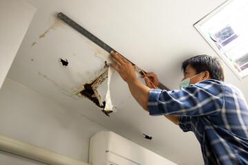 Worker repair and fixing ceiling panels damaged hole in the roof house from pipes water leakage....