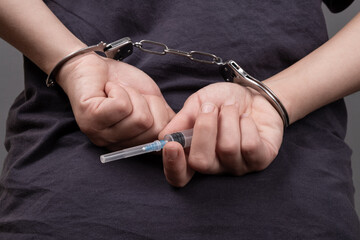 drug trafficking, a man in handcuffs with a syringe

