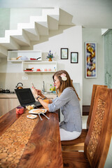 Woman using laptop and cellphone at home during breakfast - freelancing concept.