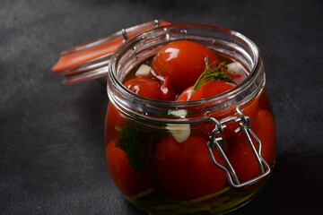 Pickled cherry tomatoes in a glass jar.