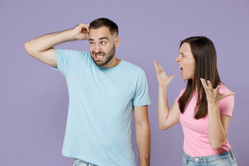 Preoccupied angry irritated young couple two friends man woman 20s in blue pink empty blank t-shirts put hand on head screaming swearing isolated on pastel violet color background studio portrait.